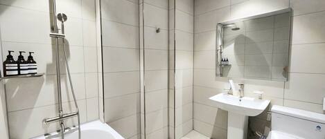 A modern bathroom with a bathtub, a shower, a sink, and a toilet.