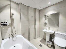 Un baño moderno con bañera, ducha, lavabo e inodoro.