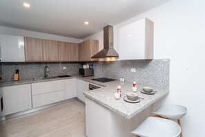 Una cocina moderna con encimeras de granito, electrodomésticos de acero inoxidable y armarios de madera.