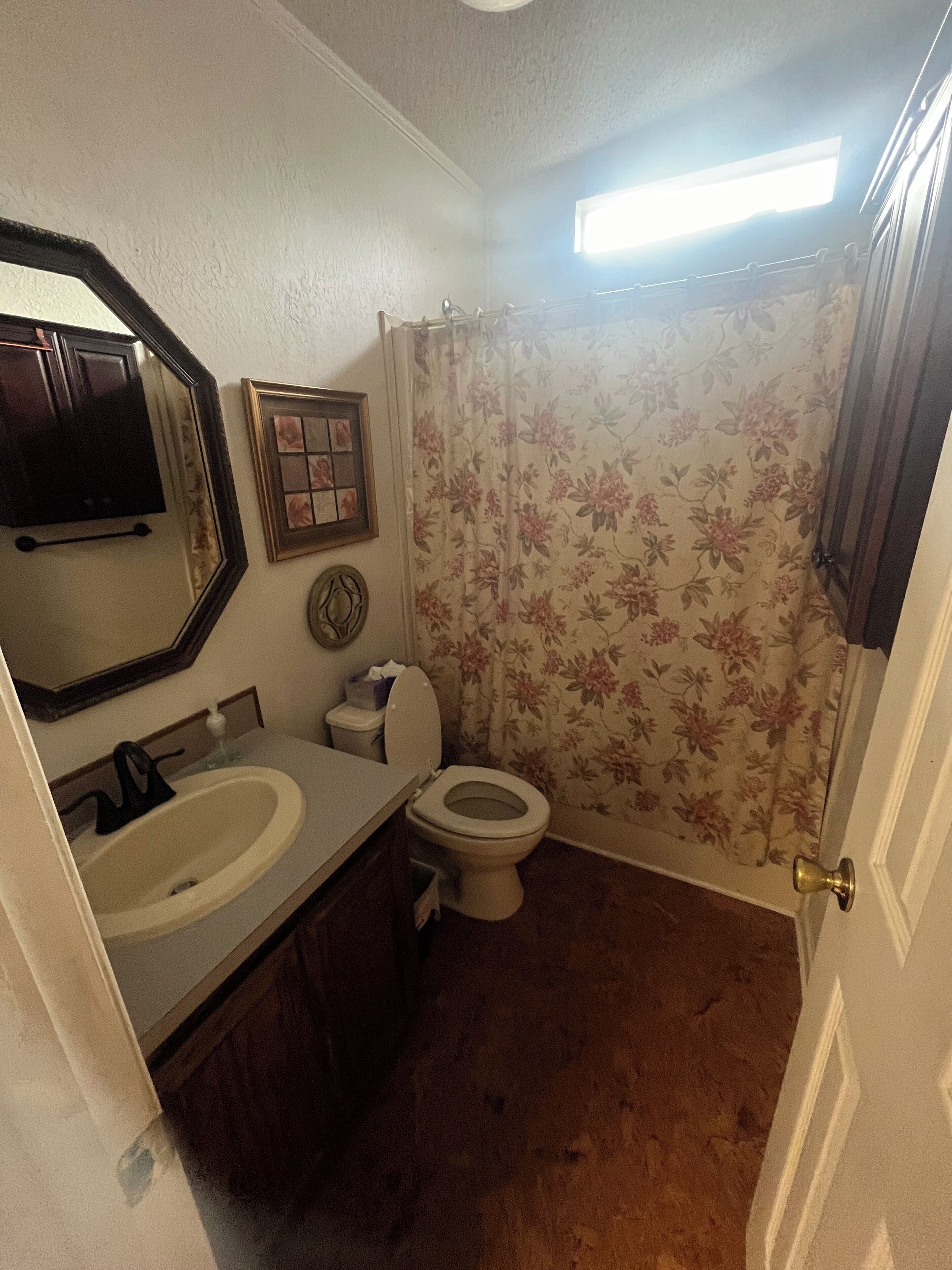 Un baño con inodoro, lavamanos y cortina de ducha.