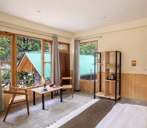 Relax in a serene space with a large bed, desk, and comfortable chair, perfect for work or reading.