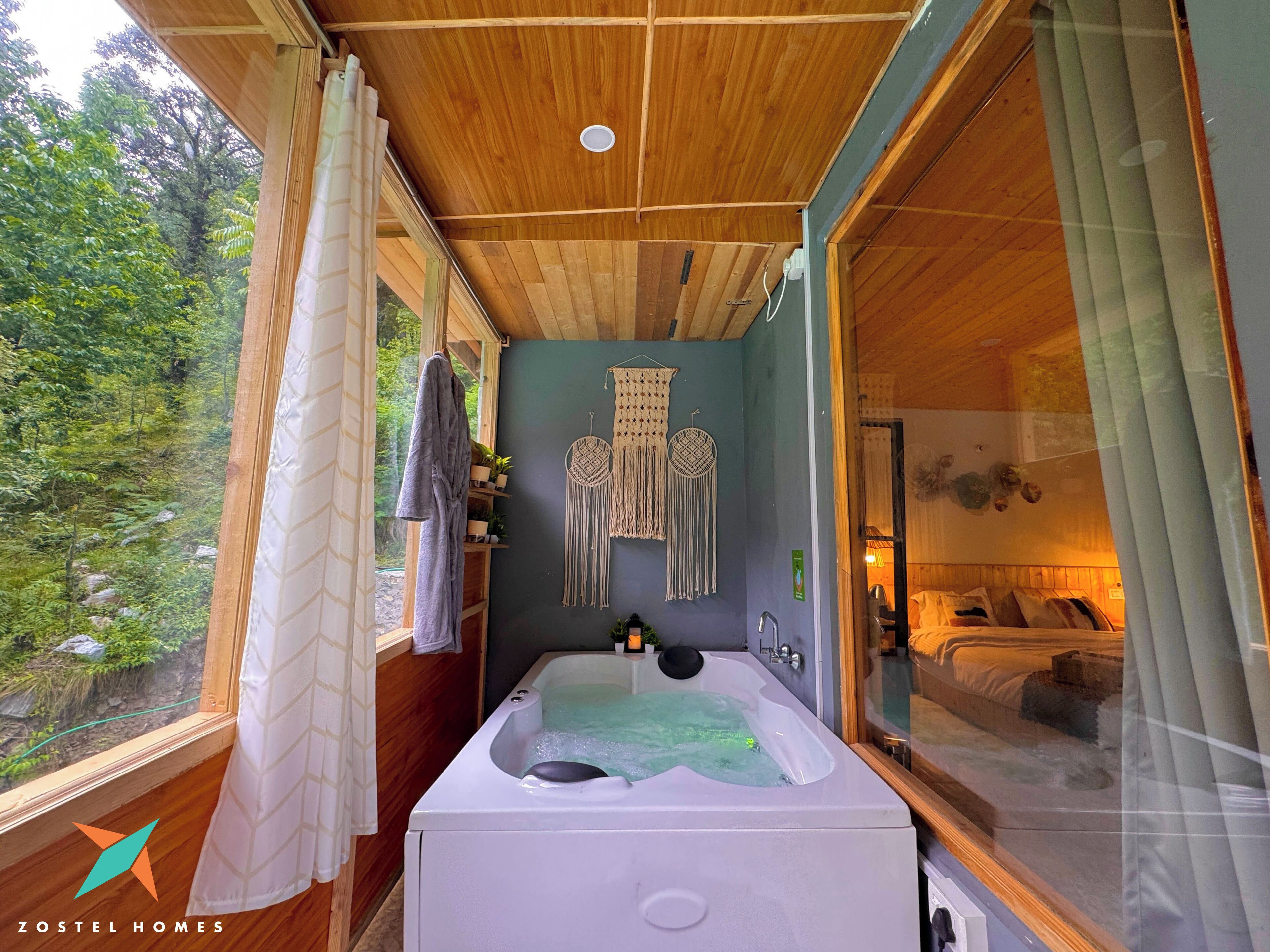 Ein Badezimmer mit Holzboden, einer Badewanne und Blick auf einen Wald durch ein großes Fenster.