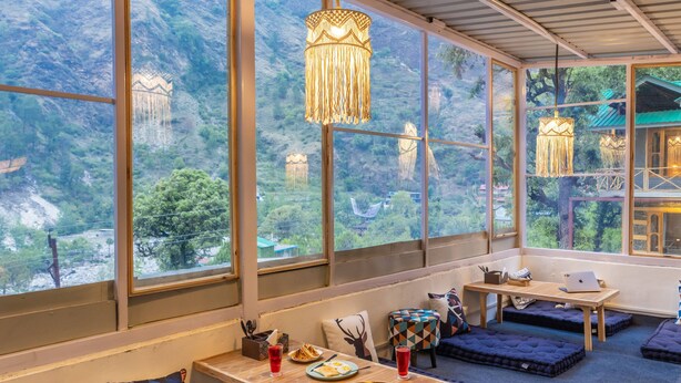 Habitación con amplios ventanales que ofrecen vistas a la montaña, una mesa de madera con productos para el desayuno y asientos acolchados.