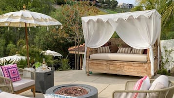 A patio with a canopy bed, outdoor furniture, and a fire pit.
