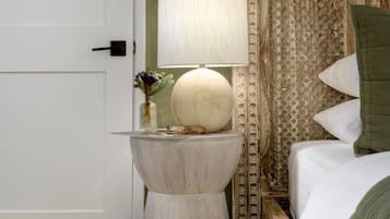 A hotel room with a bedside table, a lamp, a decorative vase, and a bed with a patterned headboard.
