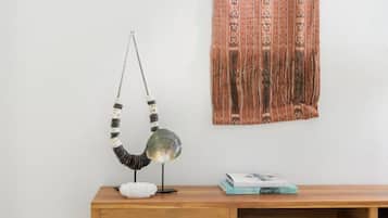 A wooden desk with a lamp and a book, against a plain wall with a patterned tapestry.