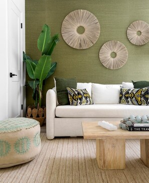 Una sala de estar con sofá, mesa de centro y decoración en la pared.