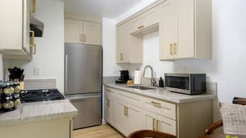 A compact kitchen with a stainless steel refrigerator, a microwave, and a gas stove.