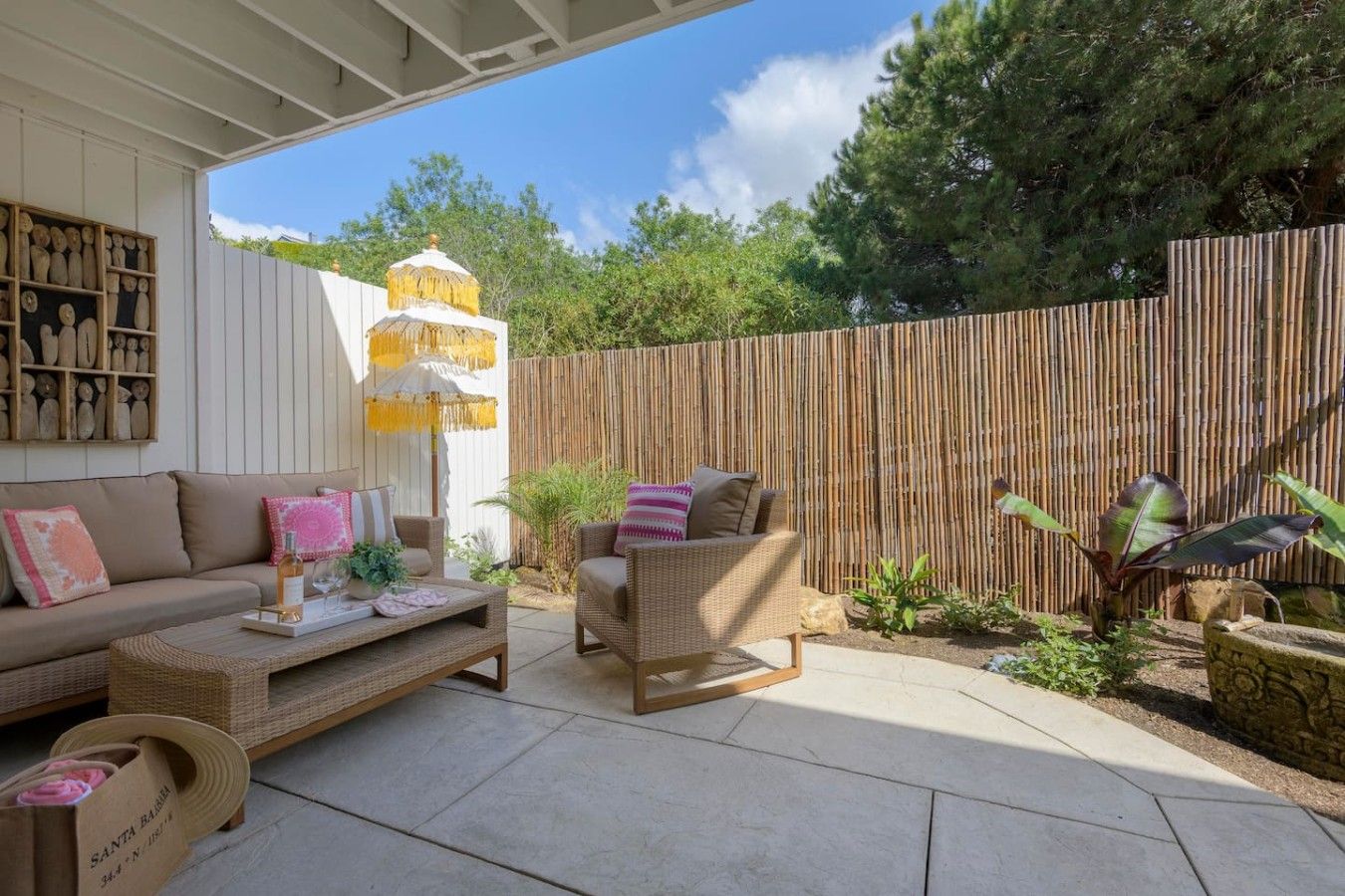 An outdoor patio area with a sofa, a chair, a table, and a decorative umbrella.