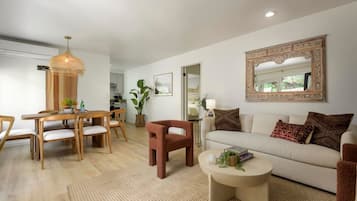 A modern living room with a dining area, a sofa set, a coffee table, and a large mirror.