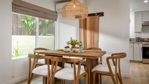 Een eethoek met een houten tafel en stoelen, een hanglamp en uitzicht op het omliggende landschap.