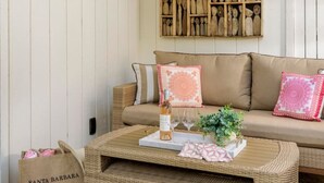 A cozy room with a wicker coffee table, a sofa with cushions, and a wall display of wooden sculptures.