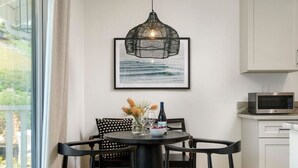 A modern kitchen with a dining area, featuring a round table with chairs, a hanging light fixture, and a microwave on the countertop.