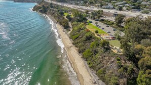 A coastal area with a beach, a road, and residential buildings.