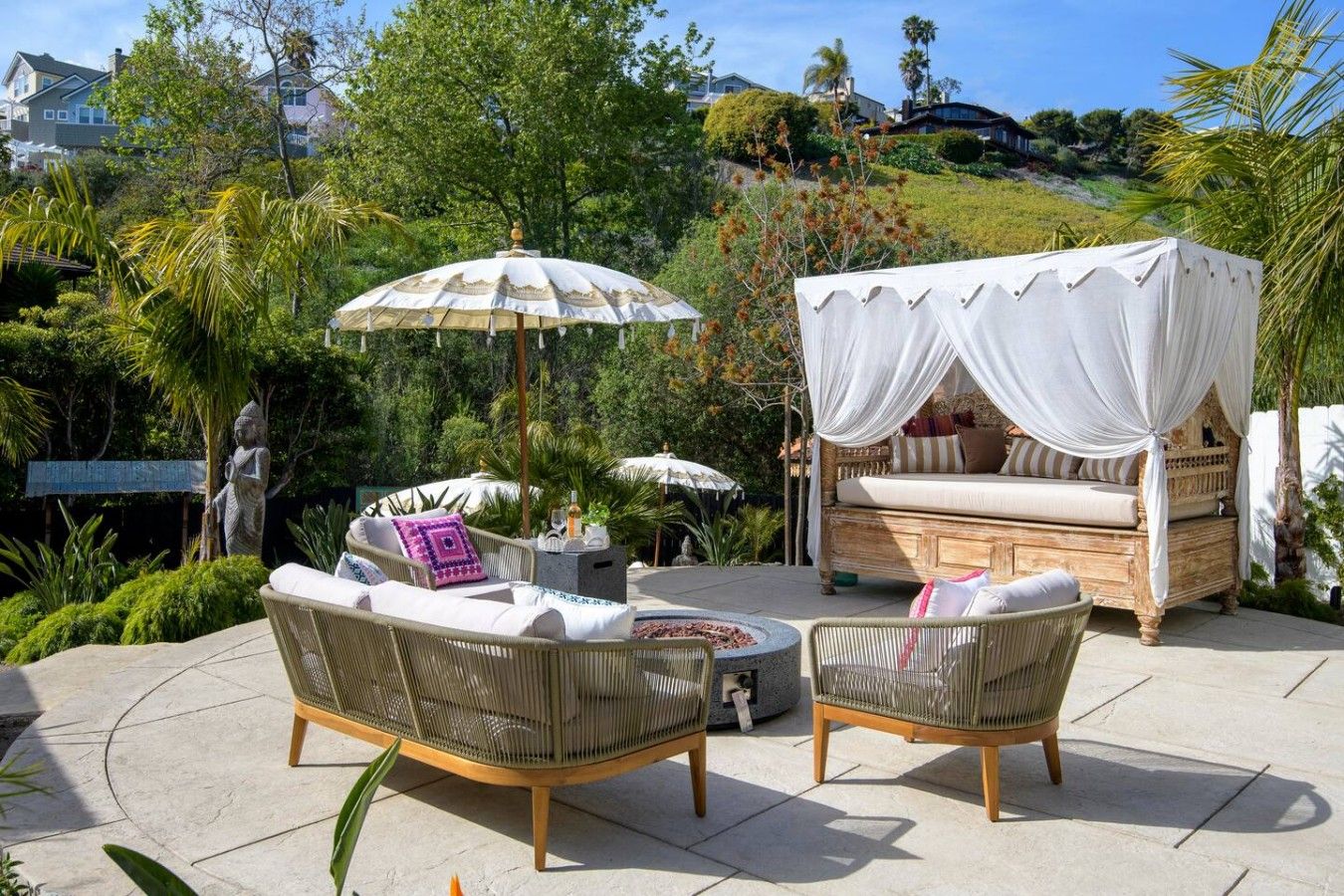 An outdoor seating area with wicker furniture, a canopy bed, and a statue.