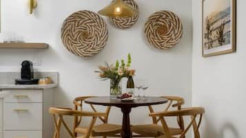 A dining area with a round table, four chairs, a pendant light, and wall decor.