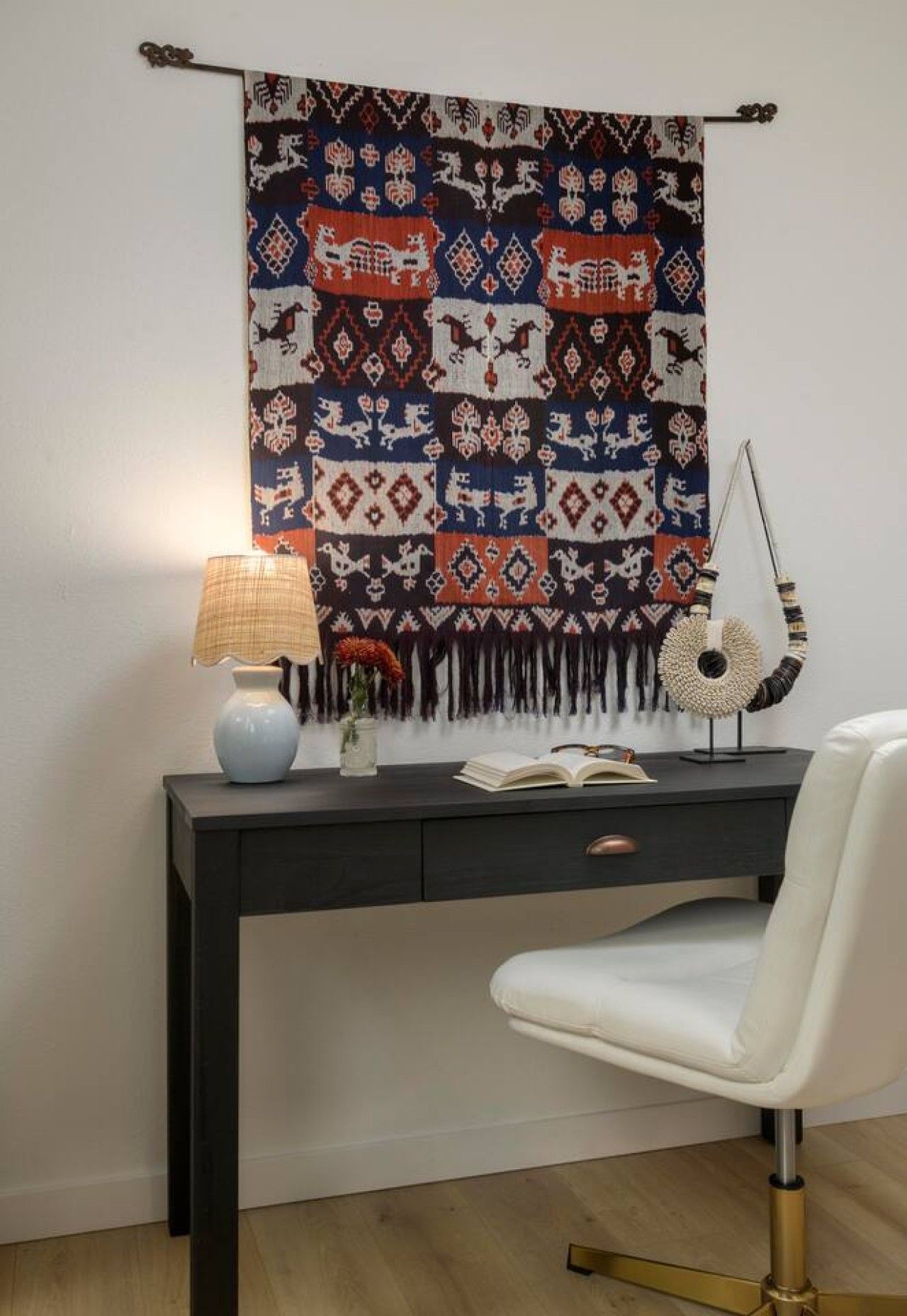 Een bureau met een lamp, een vaas met bloemen en een boek.