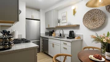 A modern kitchen with a built-in stove, microwave, and sink. There is a dining area with a wooden table and chairs.