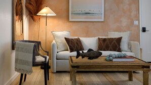 A living room with a sofa, a chair, a coffee table, a lamp, and a painting on the wall.