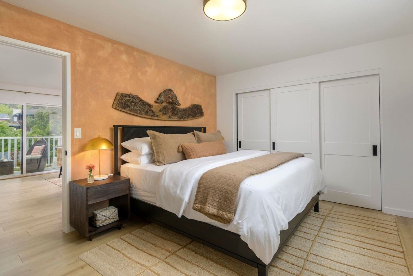 Een slaapkamer met een bed, nachtkastje en een kunstwerk aan de muur.