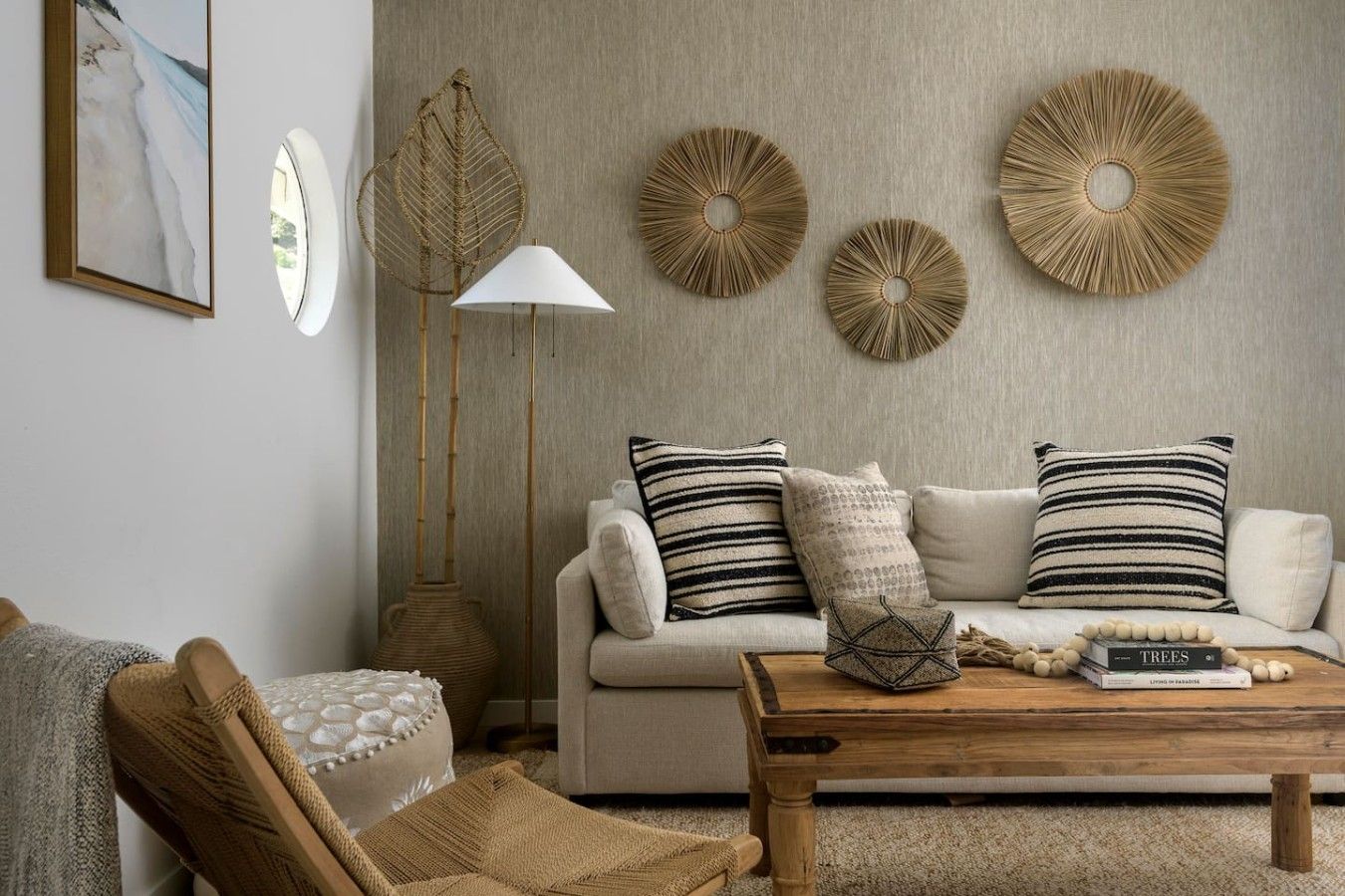 Een woonkamer met een bank, kussens, een salontafel, een vloerlamp en decoratieve wandobjecten.