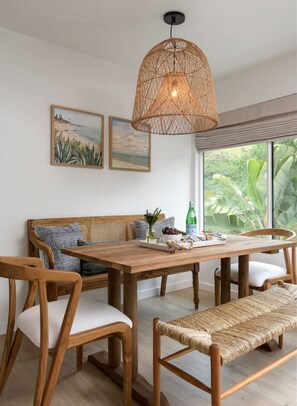A dining area with a wooden table, chairs, and a woven pendant light.
