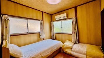 A compact room with two beds, wooden walls, and a ceiling fan.