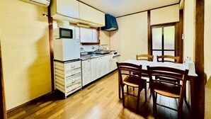 A compact kitchen with a dining table and chairs, a microwave, a stove, and a window. - Showa No Kaze⁂Complete private villa, 2 stories, the best base for Shirahama sightseeing⁂. (白浜町)