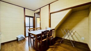 A dining area with a wooden table and chairs, a small trash bin, and a clothes drying rack against the wall. - Showa No Kaze⁂Complete private villa, 2 stories, the best base for Shirahama sightseeing⁂. (白浜町)