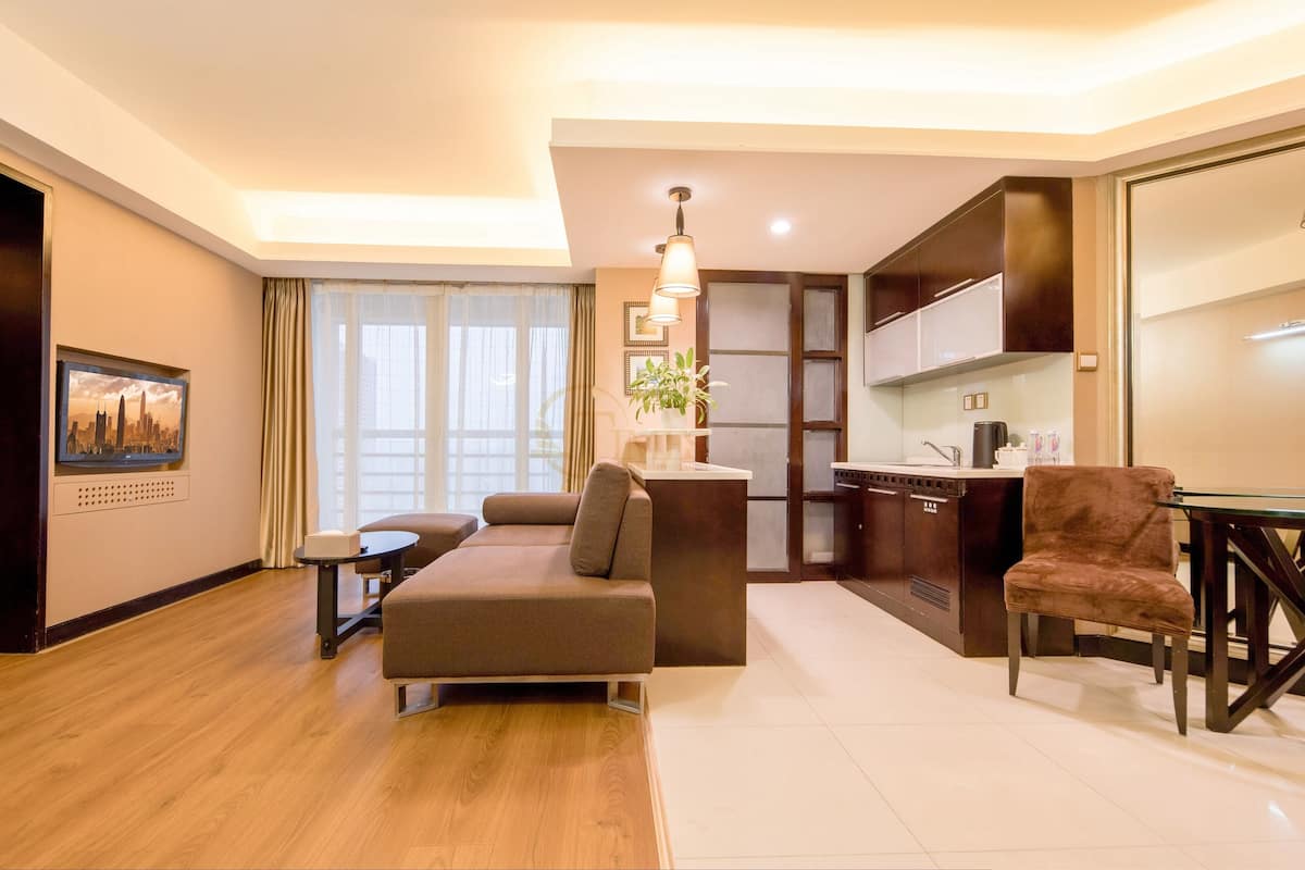 Une chambre d’hôtel moderne équipée d’un canapé, d’une petite table, d’un coin cuisine et d’une table à manger avec des chaises.