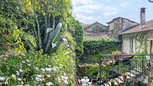 A stone building with a staircase, surrounded by greenery and flowering plants. - Nonno Luigi by Interhome (Molini di Prelà)