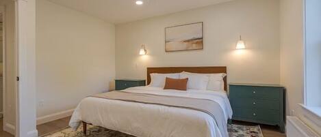 A bedroom with a bed, a ceiling fan, a nightstand, a lamp, and a window.