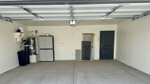 Eine saubere, leere Garage mit Wasserspender, Kühlschrank und einer Tür.