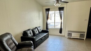 Ein Wohnzimmer mit einer schwarzen Ledersofa, einer Bank und einem Deckenventilator.