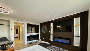 Une chambre d’hôtel moderne équipée d’un grand lit, d’un bureau, d’une chaise, d’une télévision et d’une cheminée.
