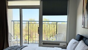 Une chambre d’hôtel avec un grand lit, un balcon avec vue et une chaise à l’extérieur.