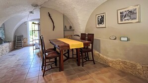 Een eethoek met een tafel, stoelen, een stenen muur en een lijst met een afbeelding aan de muur.