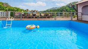 A swimming pool with a ladder, lounge chairs, and a view of mountains. - Chungju Palbong Glamping (Chungju)