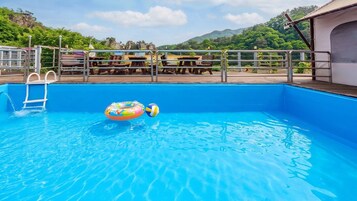 Una piscina con escalera, sillas de descanso y vistas a las montañas.