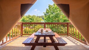 Una terrazza in legno recintata con un tavolo da picnic, una tazza e un piatto.