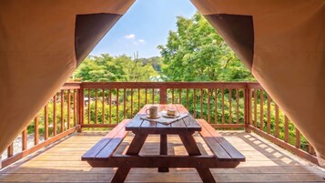 Una terraza cubierta de madera con una mesa de picnic, una taza y un plato.