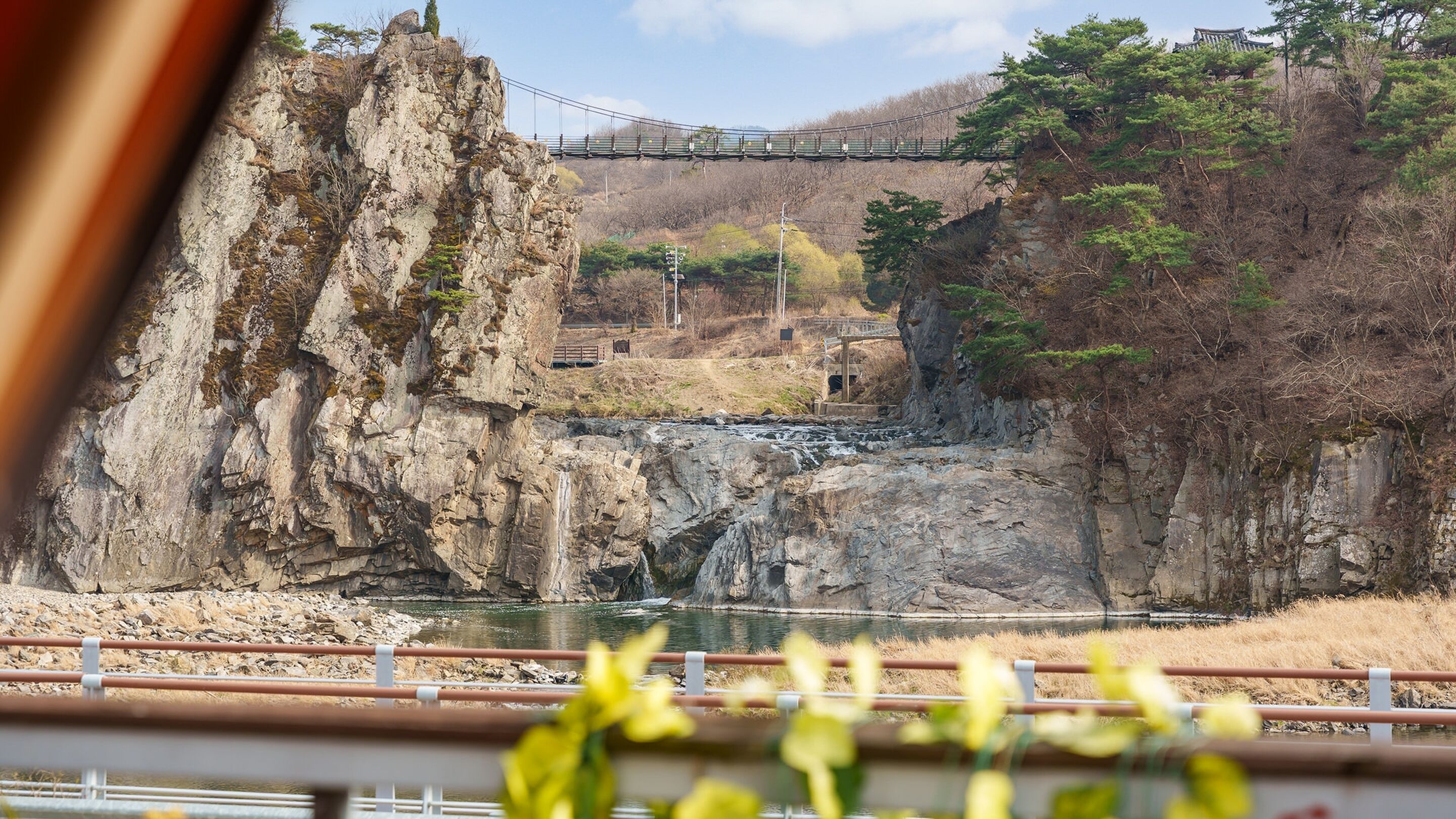 A bridge over a river with rocky cliffs and trees.