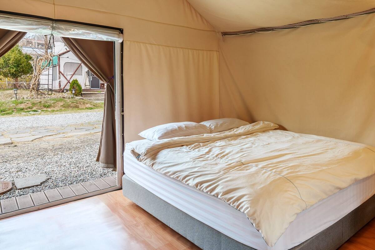 Un lit simple dans une tente, avec vue sur l’extérieur.