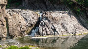 A waterfall cascading down a rocky cliff into a calm river.
