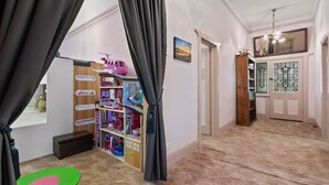 A child's playroom with a wooden playhouse, shelves with toys, and a green and pink play mat.