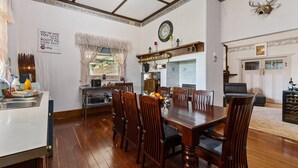 A dining area with a wooden table and chairs, a kitchen in the background, and a decorative deer head on the wall.