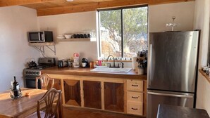 Una cocina compacta con armarios de madera, un refrigerador de acero inoxidable, un microondas y una estufa.