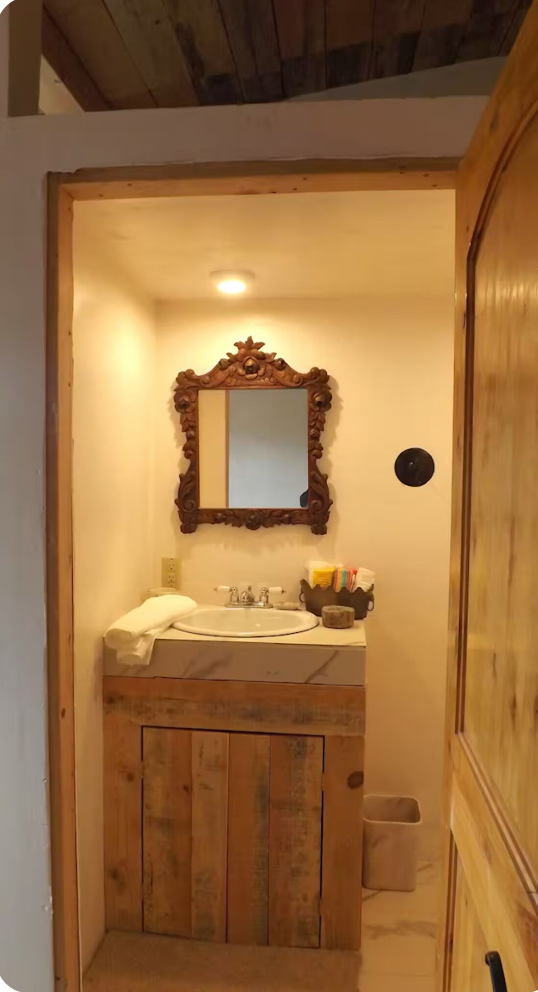 Un bagno in legno con uno specchio grande, un lavandino e un armadietto.