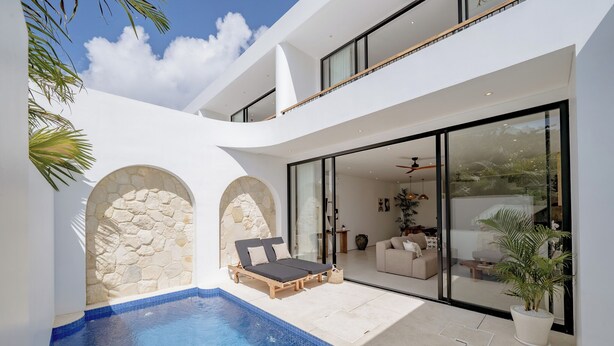 A modern house with a swimming pool, a lounge area, and a large glass door leading to a living room. - Elements A3 Villa Bingin (Pecatu)