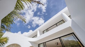 A modern building with a curved facade, large windows, and a stone archway. - Elements A3 Villa Bingin (Pecatu)